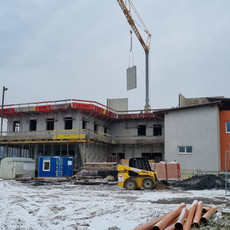 Bauarbeiter bedienen einen Kran, um eine große Betonplatte auf der Baustelle des VIBA Points im Gewerbepark Kemeten zu platzieren.
