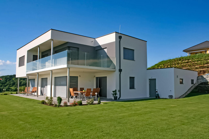 Modernes Ziegelmassivhaus in einer grünen Landschaft, symbolisiert Nachhaltigkeit