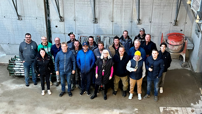 Gruppenfoto von lächelnden Mitarbeitern und Partnern bei einem Baustellenfest im Inneren des Rohbaus.