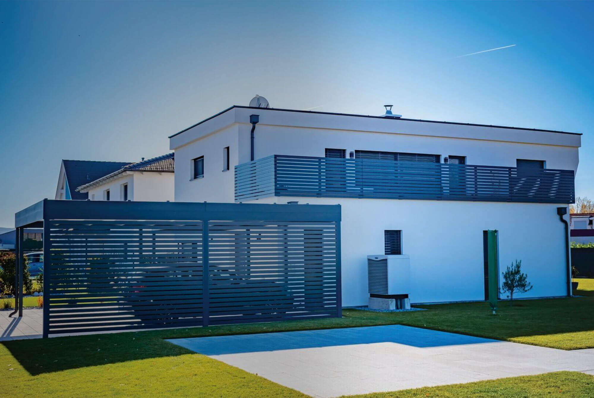 Modernes weißes Einfamilienhaus mit Balkon und Carport.